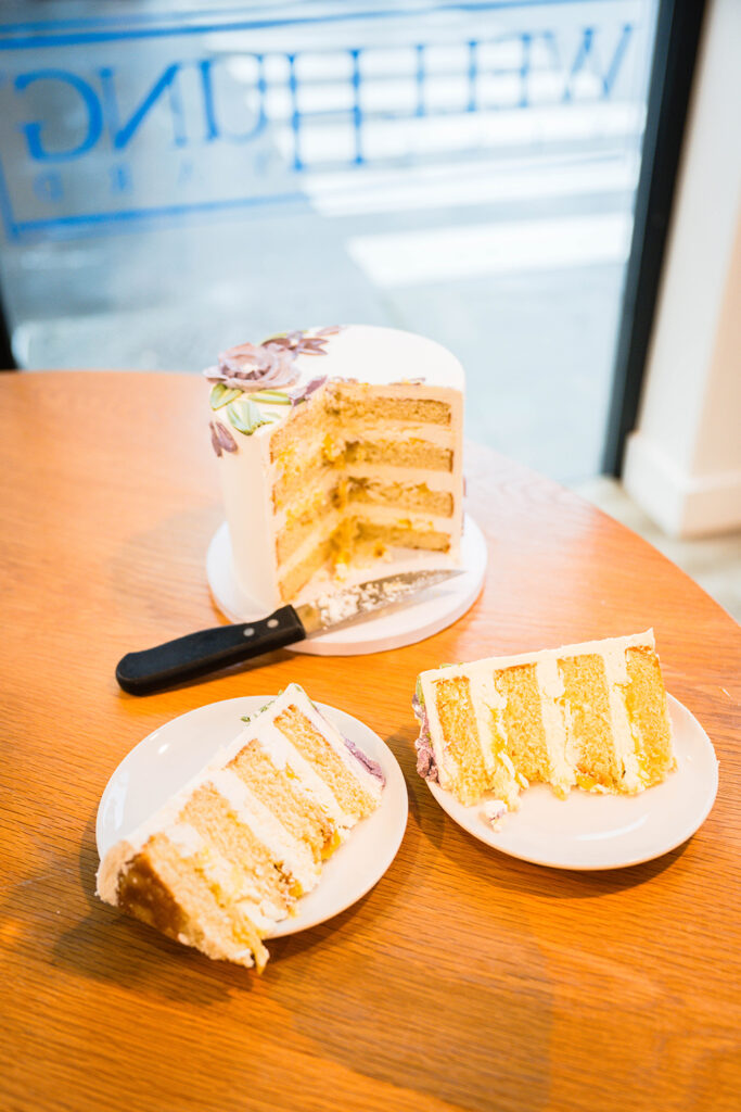 A wedding cake with two slices of cake cut out and placed on plates.