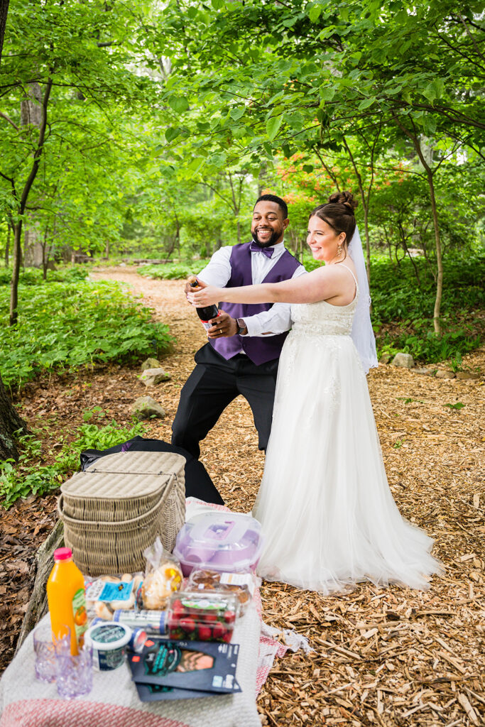 A couple prepares to pop a bottle of champagne in Mill Mountain Wildflower Garden to celebrate getting married.