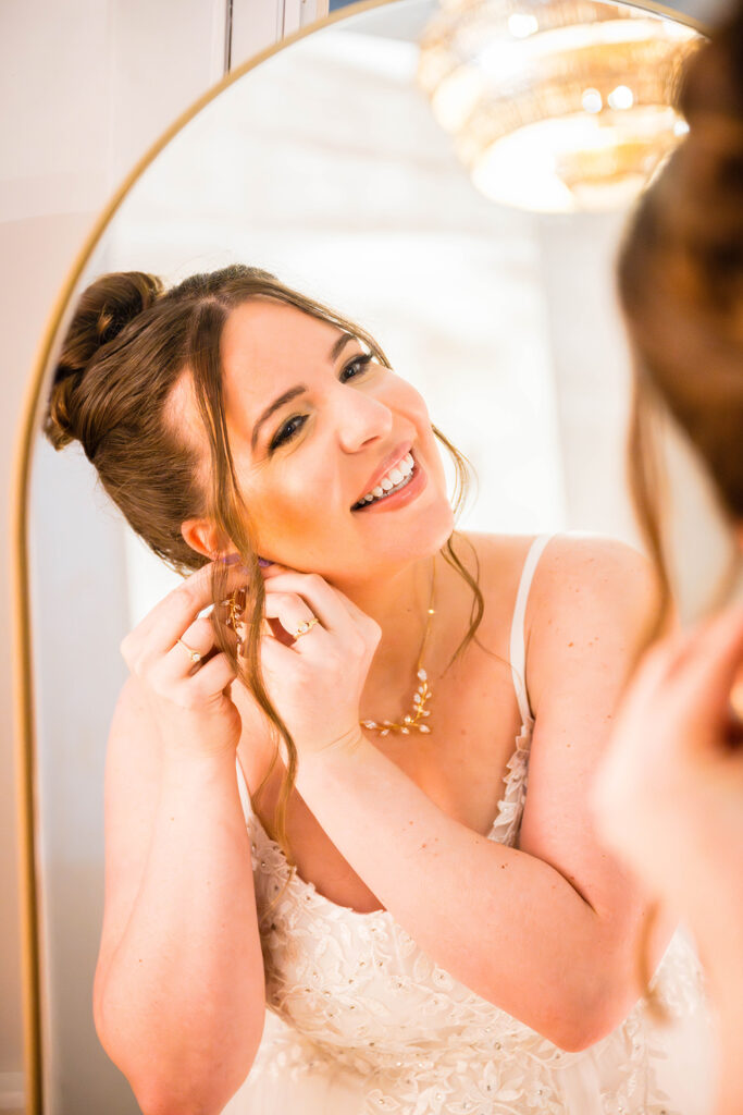 A woman admires herself in the mirror as she puts in her earrings.