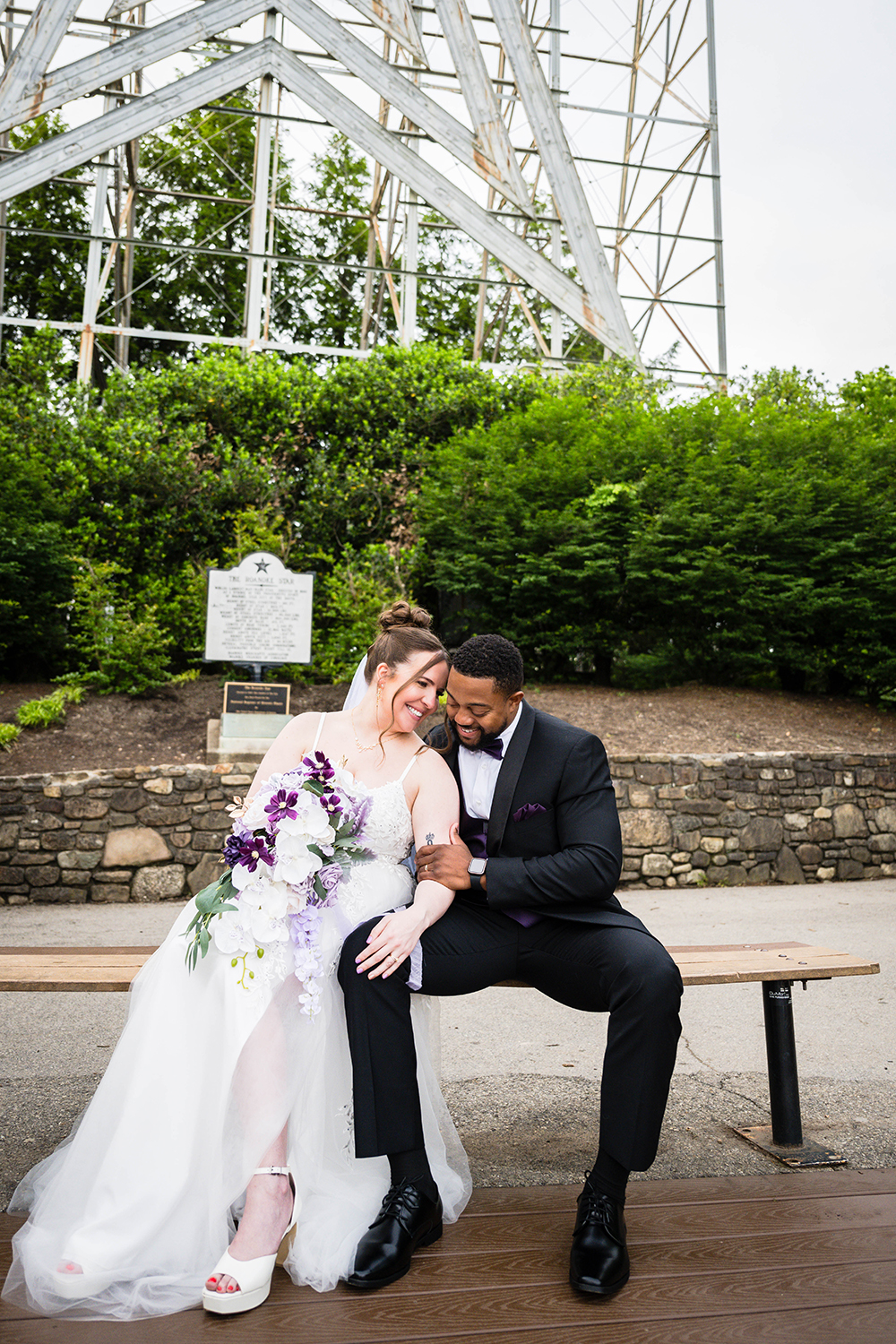 A couple on their elopement day sit on a bench in front of the Mill Mountain Star in Roanoke, Virginia.