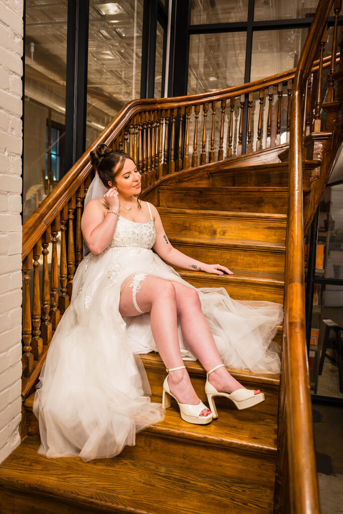 A woman sits in a stairwell wearing a wedding dress on her elopement day.