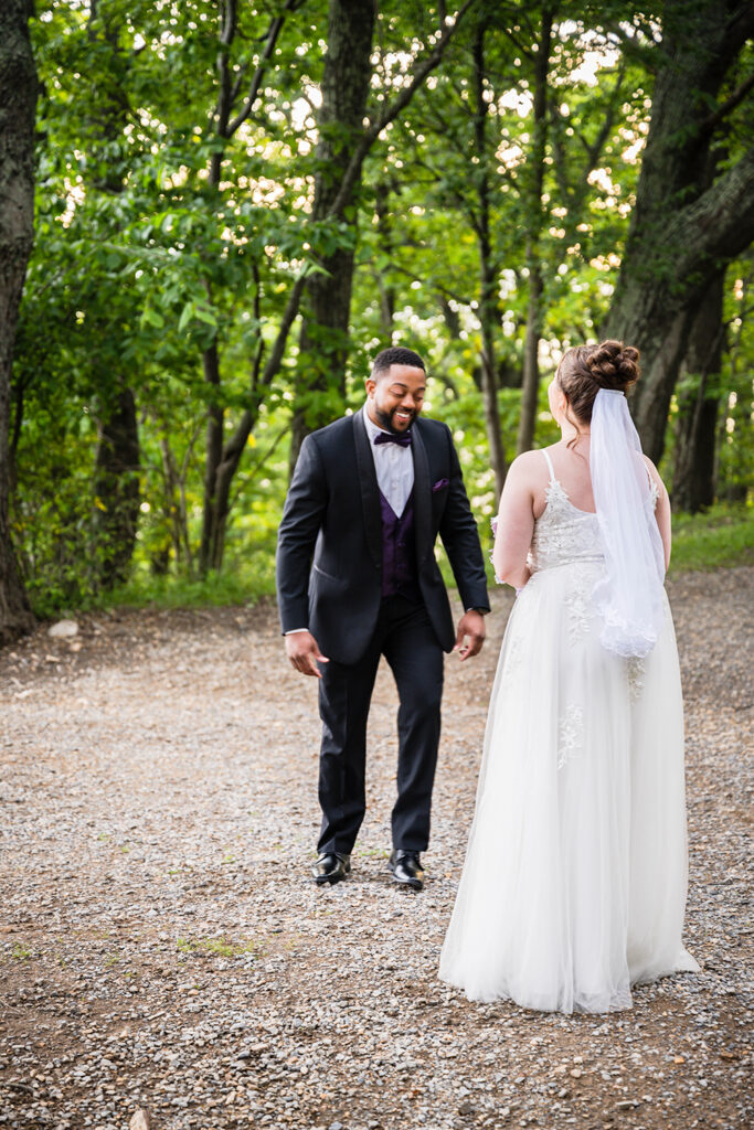 A man reacts to seeing his partner in a wedding dress with her hair and makeup done during their first look on their elopement day.