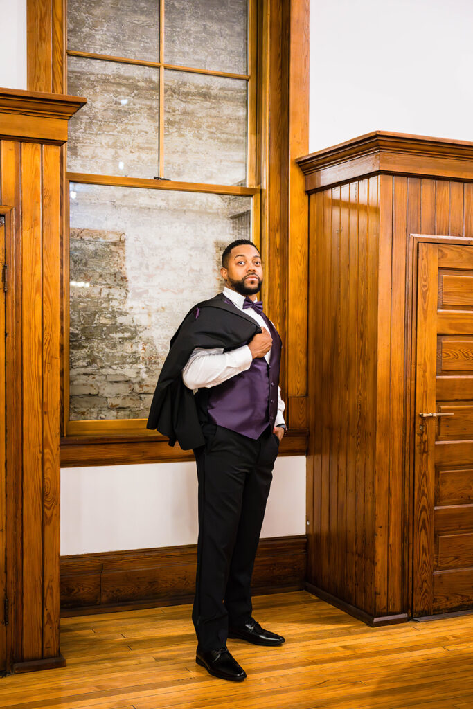 A man stands in a hotel lobby for a photo on his elopement day.