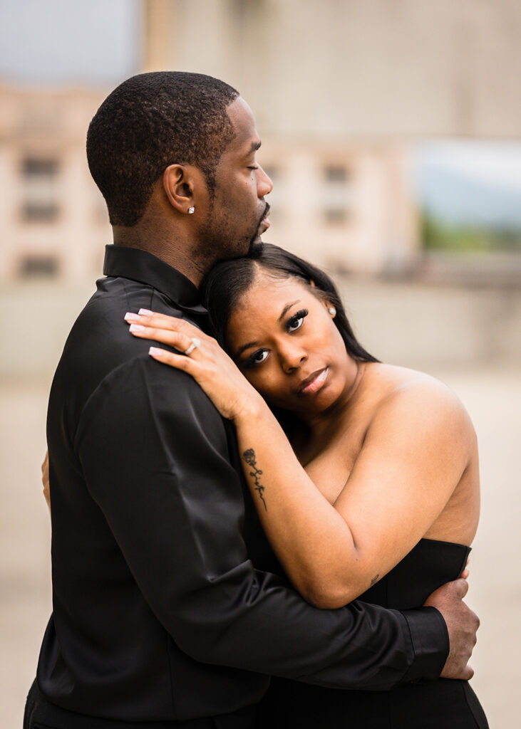 A Black woman rests her head on her partner's chest while her partner closes his eyes and takes a deep breath.