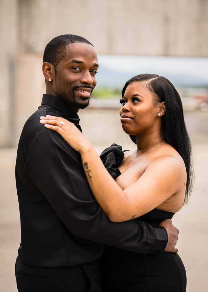 A Black woman looks at her fiancé lovingly during their engagement photo session in Downtown Roanoke.