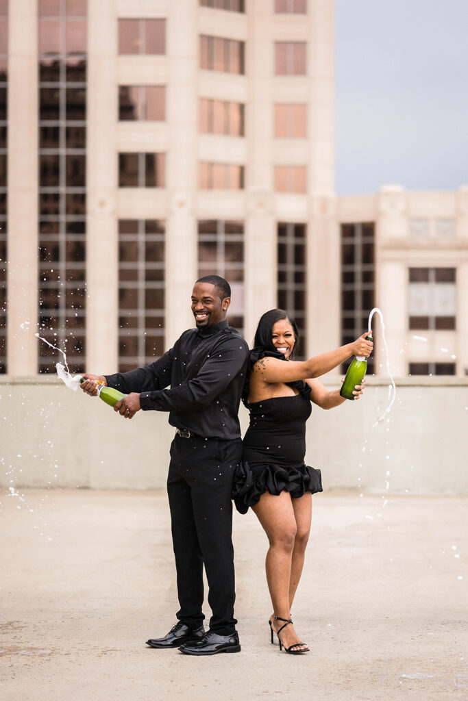 A Black man and woman pop champagne during their engagement photo session in Roanoke, Virginia.