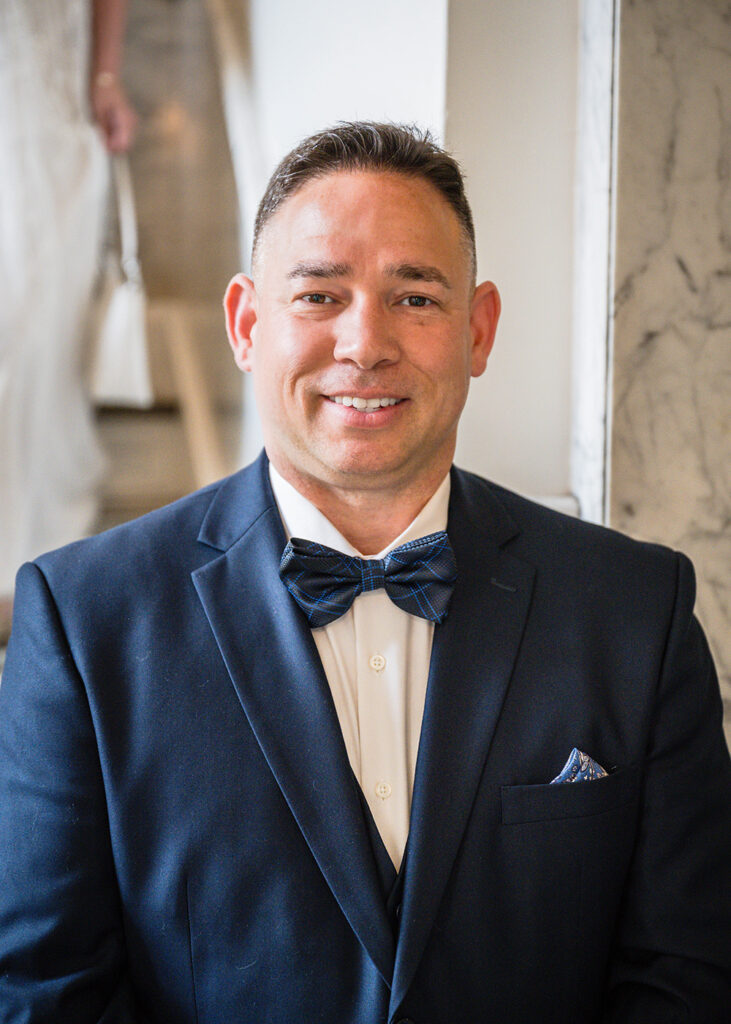 A groom smiles at the end of the stairs waiting for the bride to reveal herself during their first look at the Liberty Trust Hotel in Downtown Roanoke.