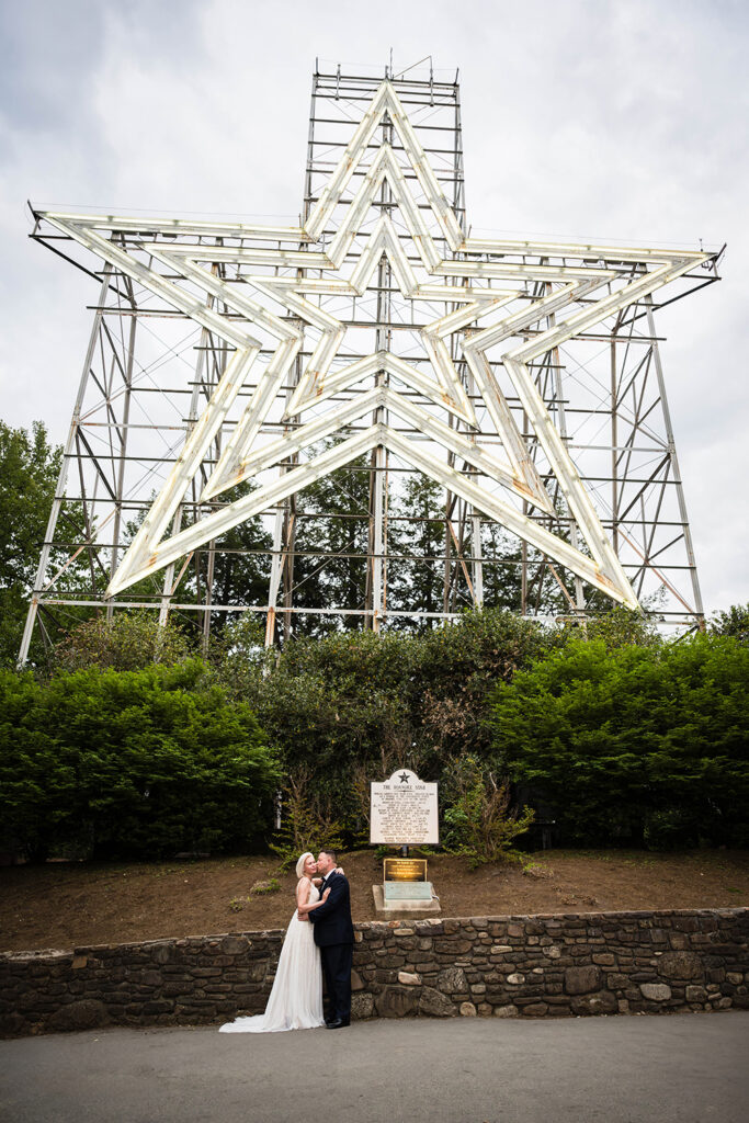 A wedding couple poses with the illuminated Mill Mountain Star in Roanoke, Virginia.
