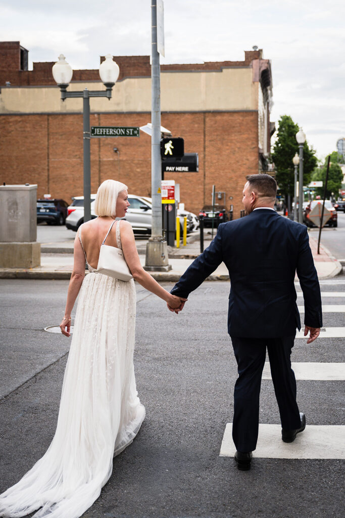 A wedding couple walk hand-in-hand in a crosswalk in Roanoke, Virginia.