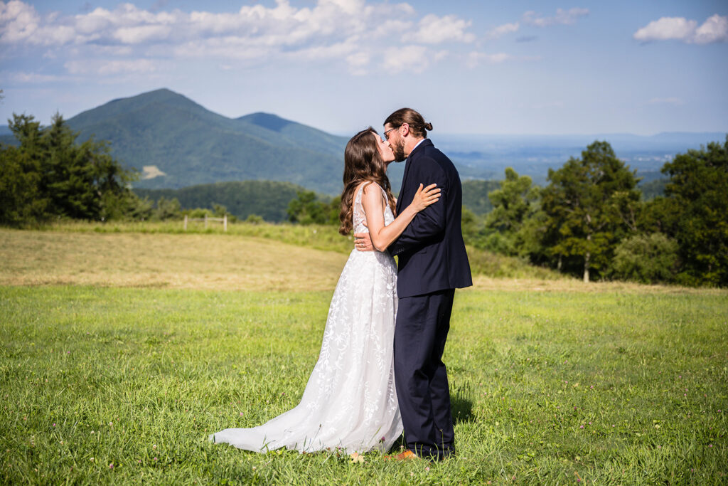 An elopement couple has their first kiss during their Blue Ridge mountain wedding ceremony at Cahas Mountain Overlook.