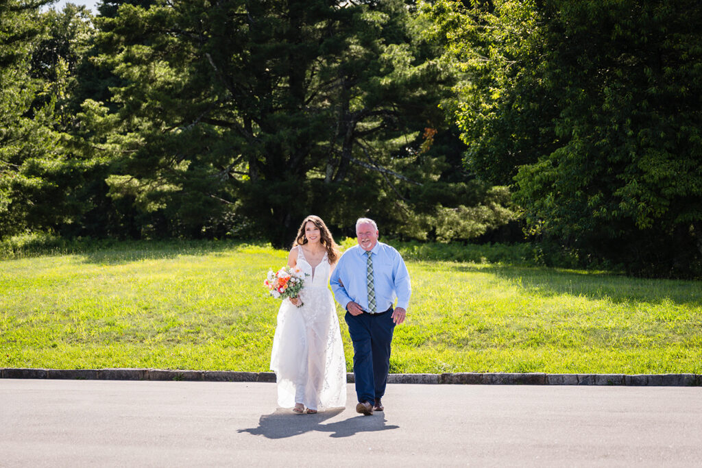 A bride links arms with her Dad and he walks her down the aisle for her Blue Ridge mountain wedding day.