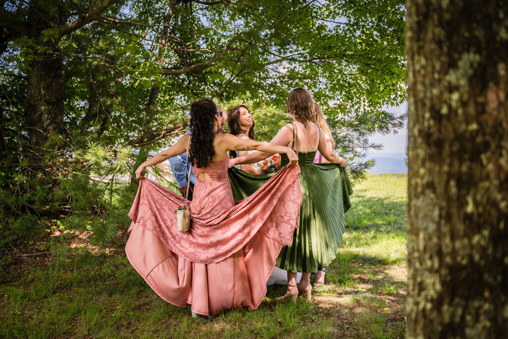 Three women surround the bride and use their long dresses as a curtain to hide the bride from view of the road.