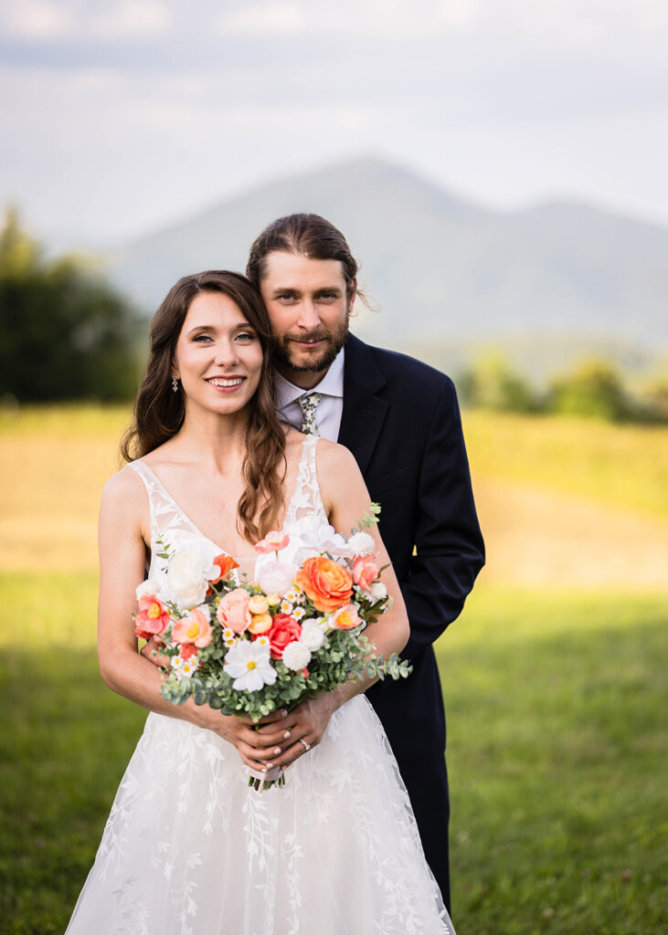 An elopement couple pose together for a Blue Ridge Parkway wedding portrait at golden hour in front of Cahas Mountain.