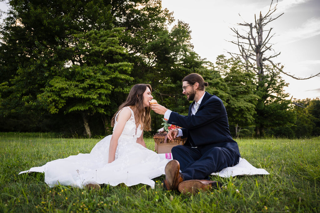 A marrier feeds his partner a cupcake and smiles softly as she takes a bite.