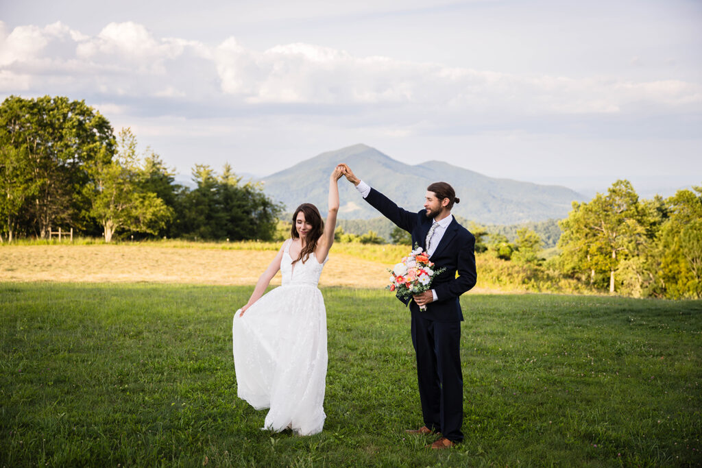 A man holds onto a wedding bouquet and twirls a woman admiringly as she twists and holds her wedding dress.