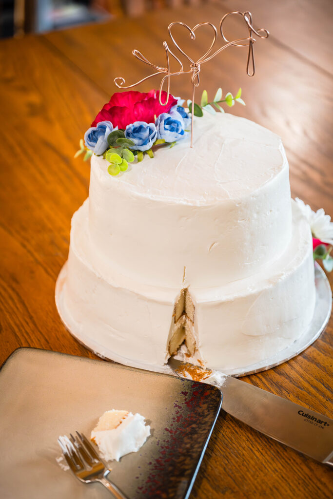 A small sliver of wedding cake cut out of a cake is placed on a plate.