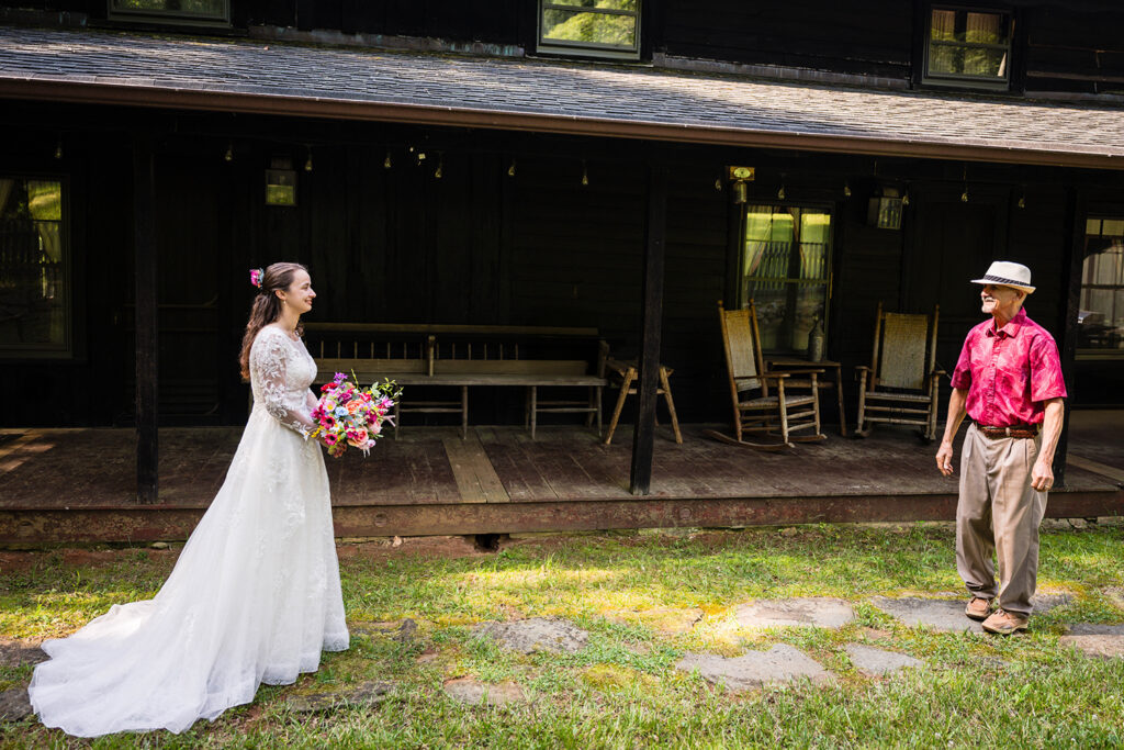 A marrier in a wedding dress holding a bouquet smiles in anticipation as her Dad turns to face her during their first look.