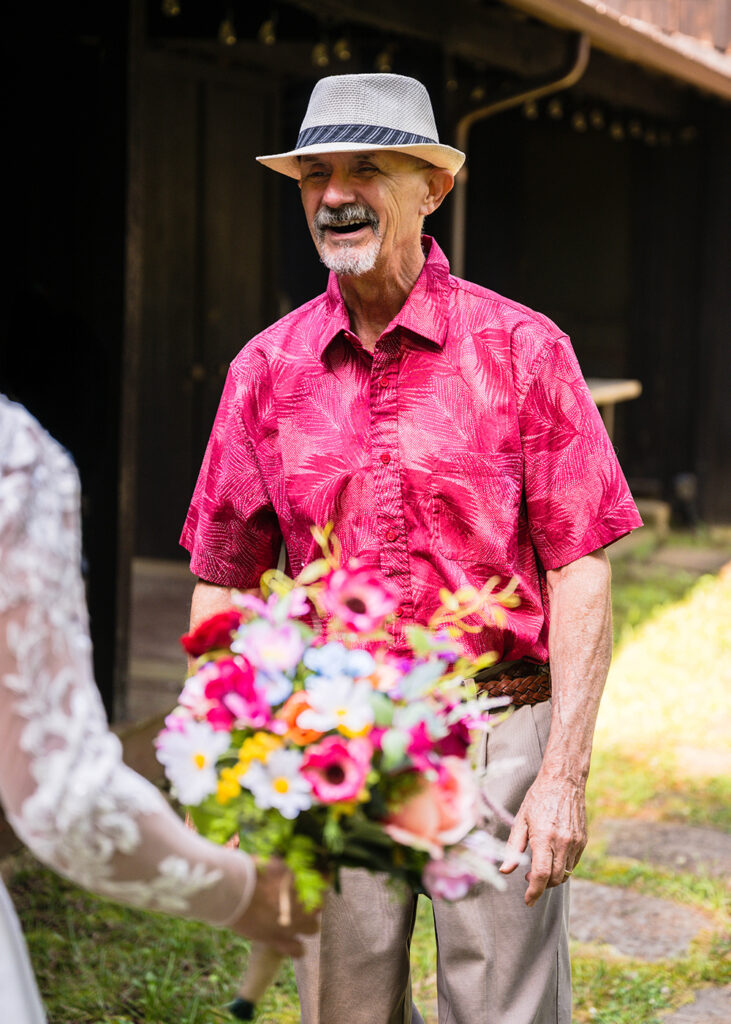 The father of the bride smiles widely as he turns to face his daughter during an elopement day first look.