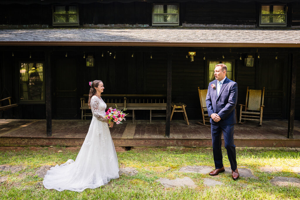 A groom reacts to seeing a bride in her wedding dress for the first time. His mouth is formed in the shape of an O.