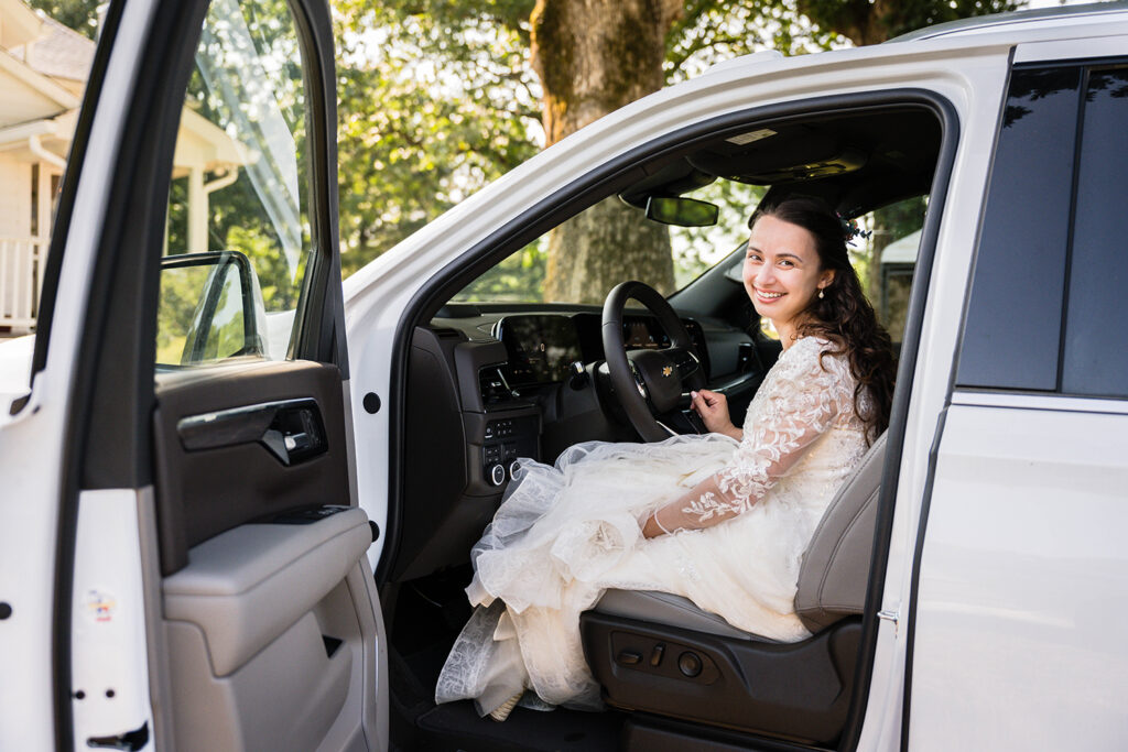 A marrier wearing a wedding dress sits in the driver's seat of a Chevy Tahoe during her Martinsville, Virginia elopement day.