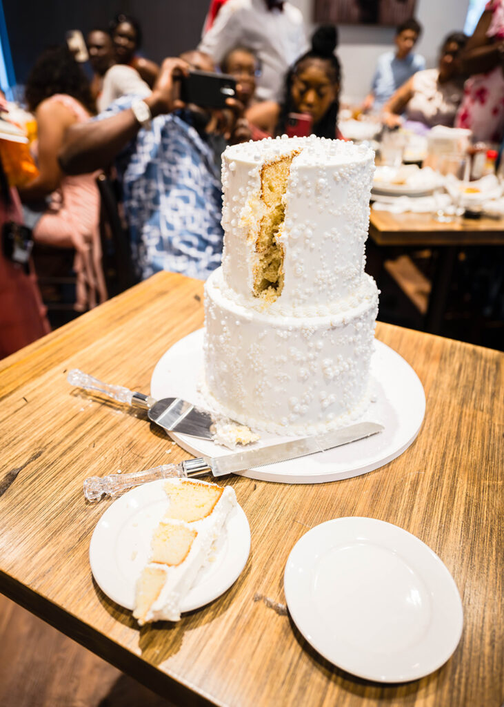 A two-tier wedding cake with a slice of cake cut out and placed on a plate.