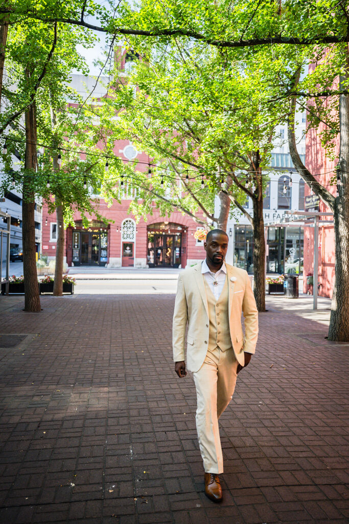 A man wearing a tan suit walks down the aisle of his Downtown Roanoke wedding at Century Plaza.