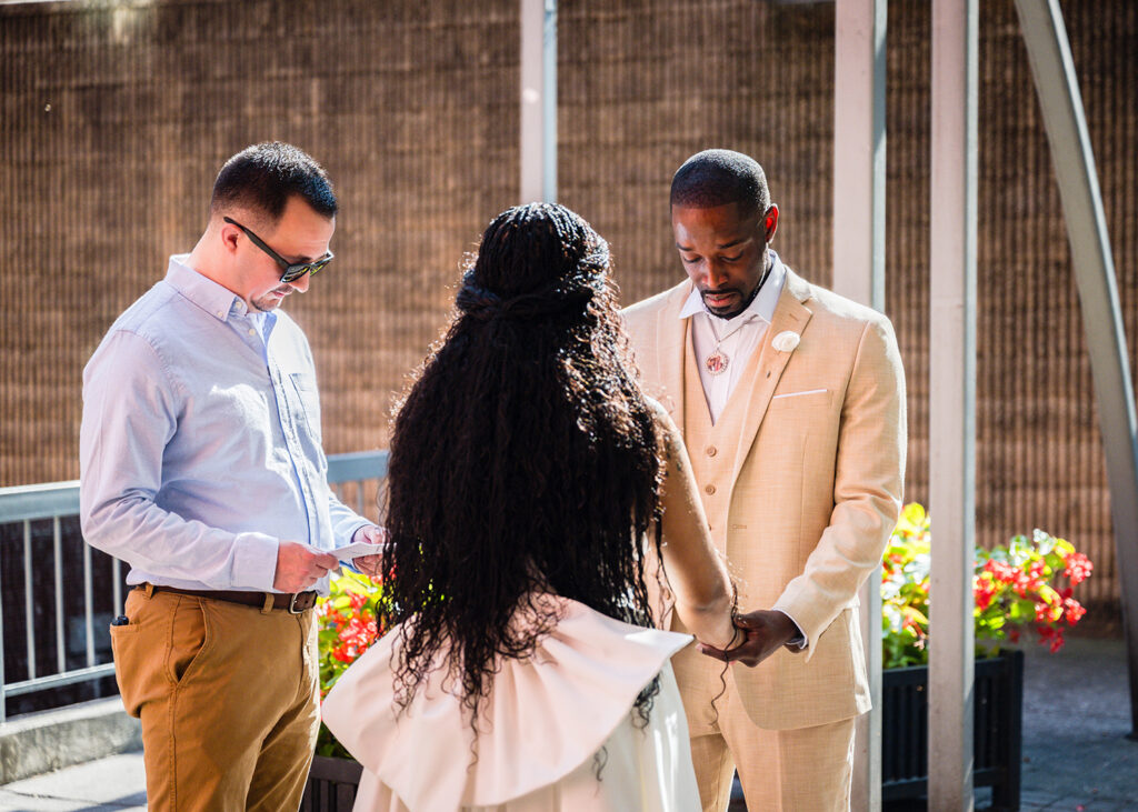 A bride and groom join hands as their ceremony starts at Century Plaza. The groom is holding back tears.