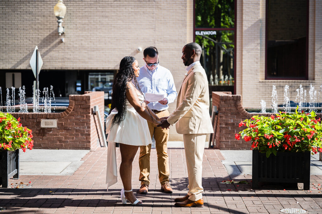 An elopement couple join hands at the altar with their officiant during their Downtown Roanoke wedding at Century Plaza.