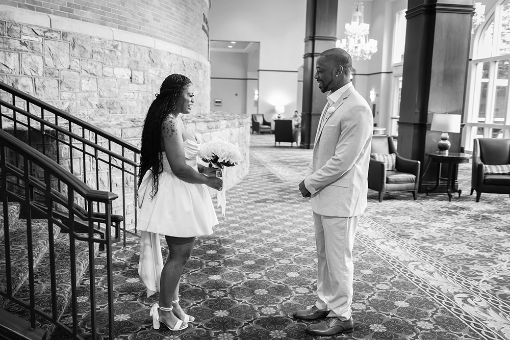 A bride smiles widely as the grooms turns around to see his soon-to-be wife in her wedding dress for the first time.