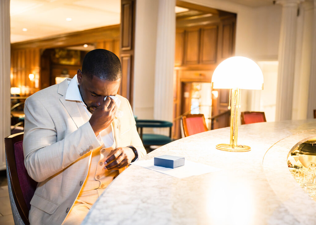 A man wipes away tears after opening a surprise gift from his soon-to-be wife at Hotel Roanoke.