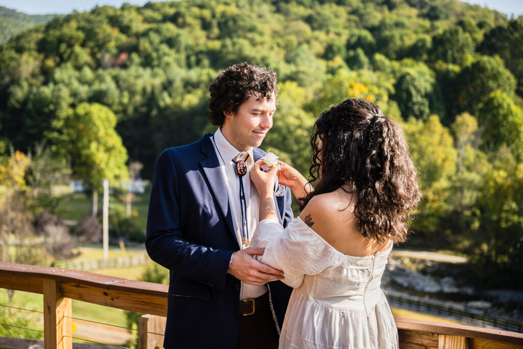 A woman adjusts a boutonniere on her partner's suit lapel.