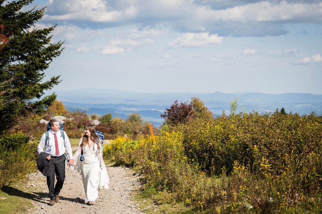 A wedding couple hold hands and smile at one another as they hike Massie Gap.
