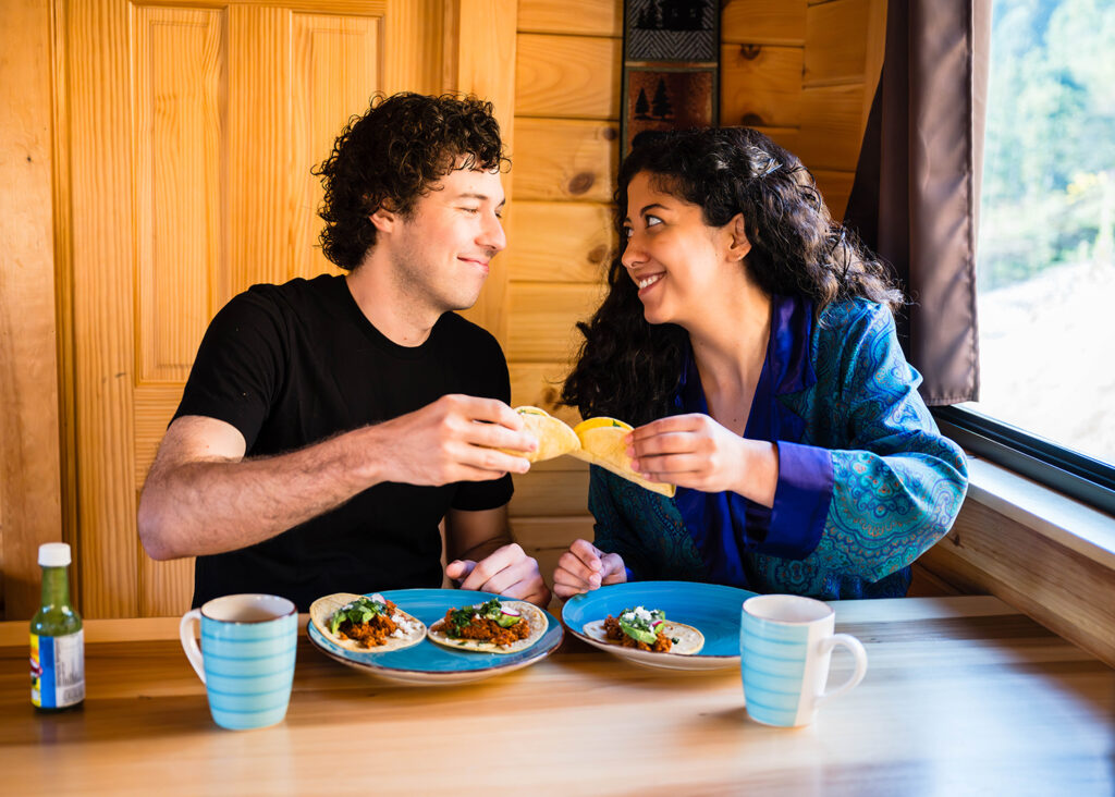 A couple "cheers" their breakfast tacos inside of a cabin near Grayson Highlands.