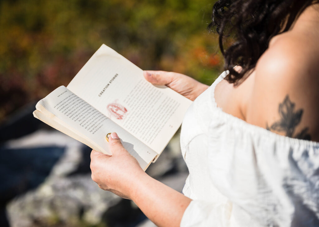 A marrier holds open a book while holding onto their significant other's wedding band.