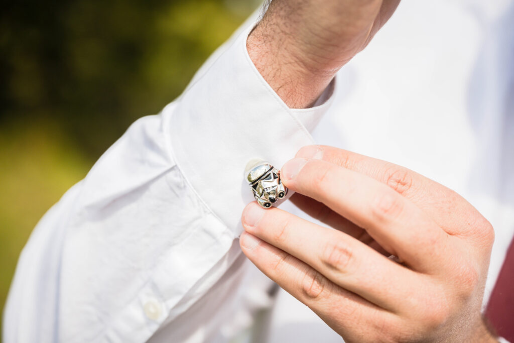 A man shows off his Star Wars cufflinks for a photo.