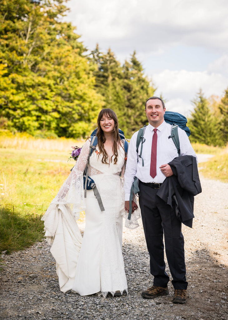 A wedding couple poses for a photo with their hiking gear at Massie Gap in Grayson Highlands State Park in Virginia.