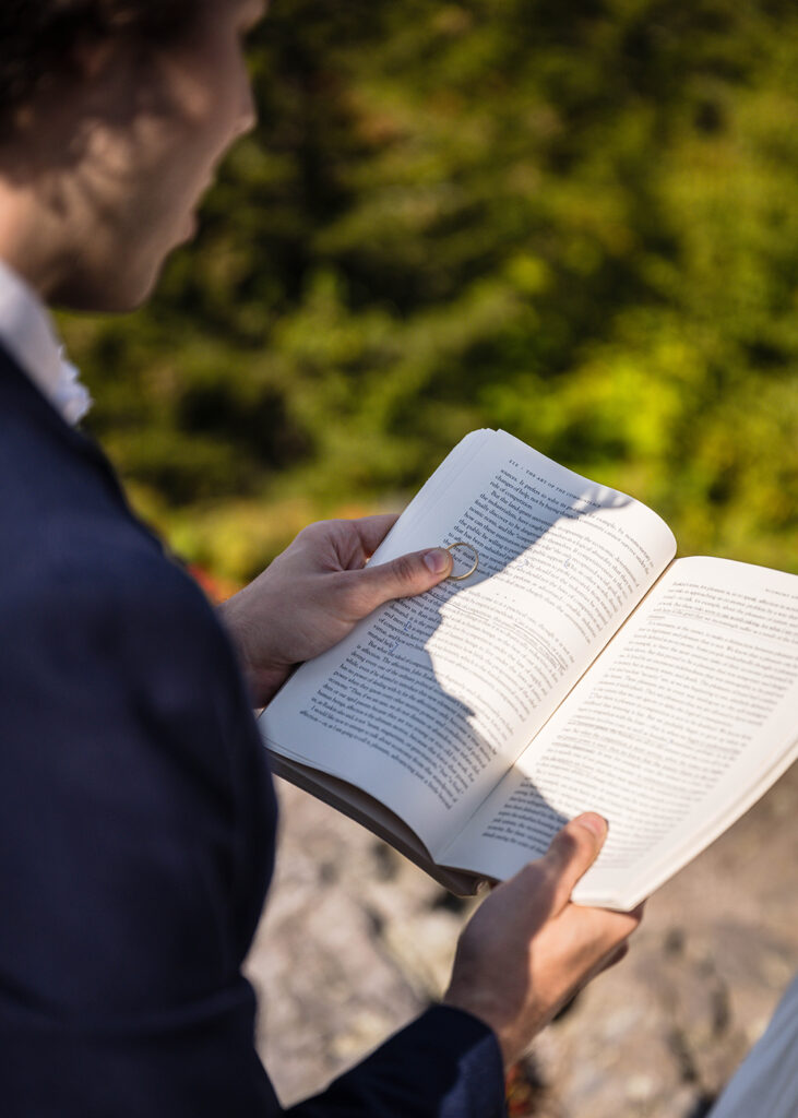 A marrier holds open a book while holding onto their significant other's wedding band.