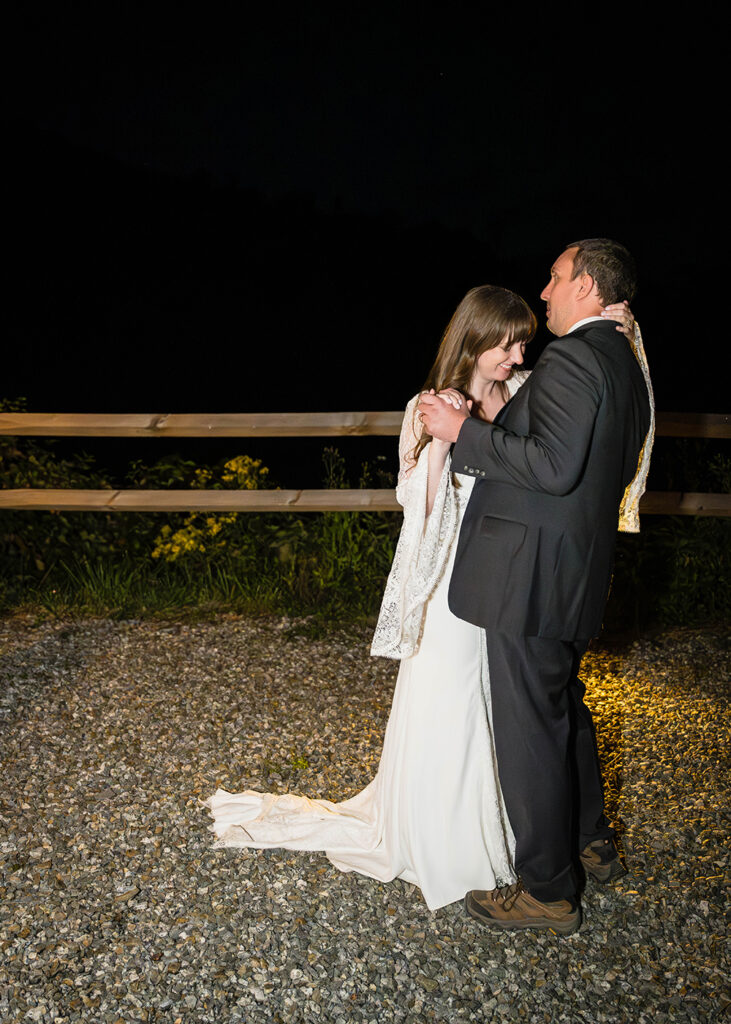 A wedding couple on their elopement day has their first dance outside of their Airbnb at Highland Hideaways under the night sky.