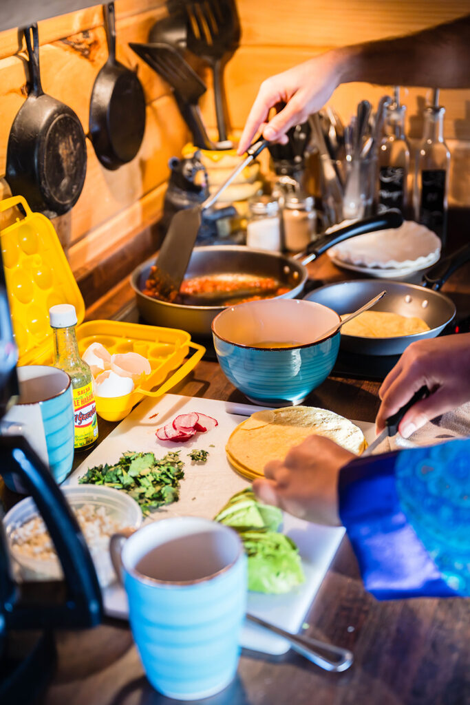 A couple starts making breakfast tacos in the kitchen of their Airbnb at Highland Hideaways.
