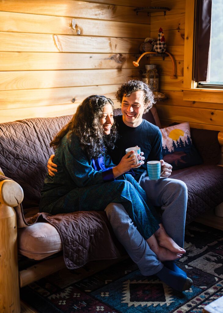 A couple enjoy cups of coffee while sitting on a couch at Highland Hideaways.