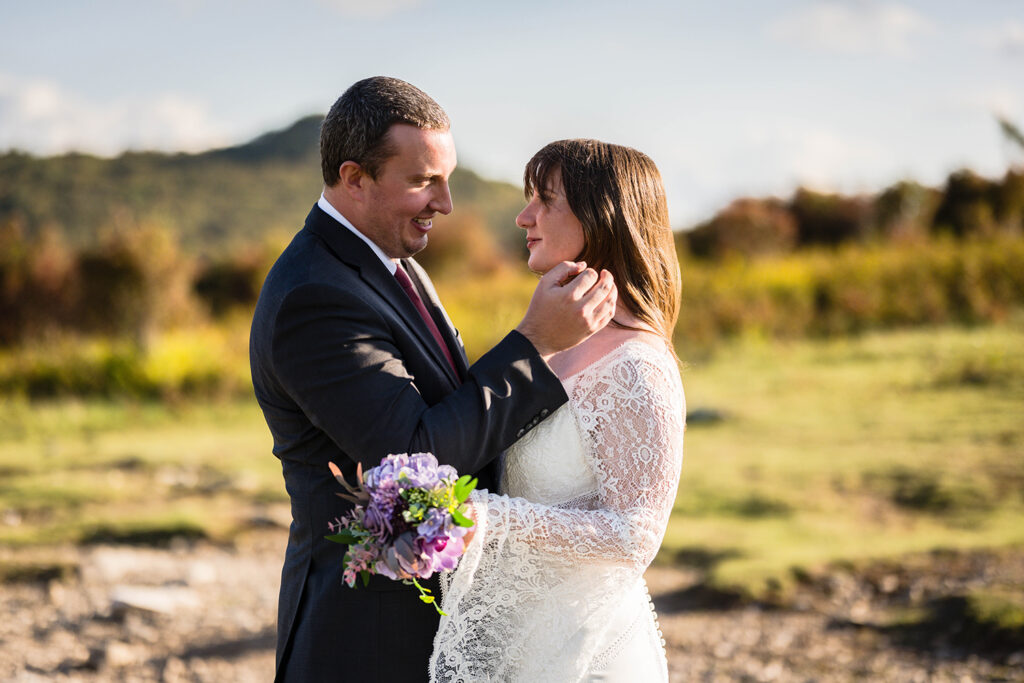 A groom wipes hair away from a bride's face.