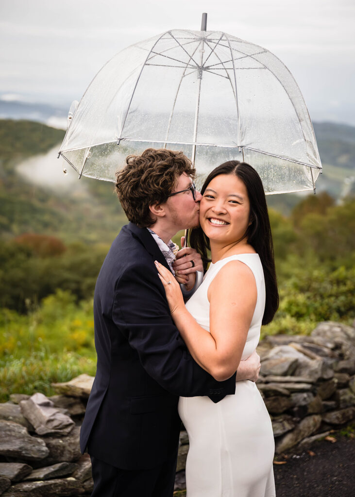 An LGBTQ+ elopement wedding couple pose together under an umbrella for a portrait at Grayson Highlands State Park.