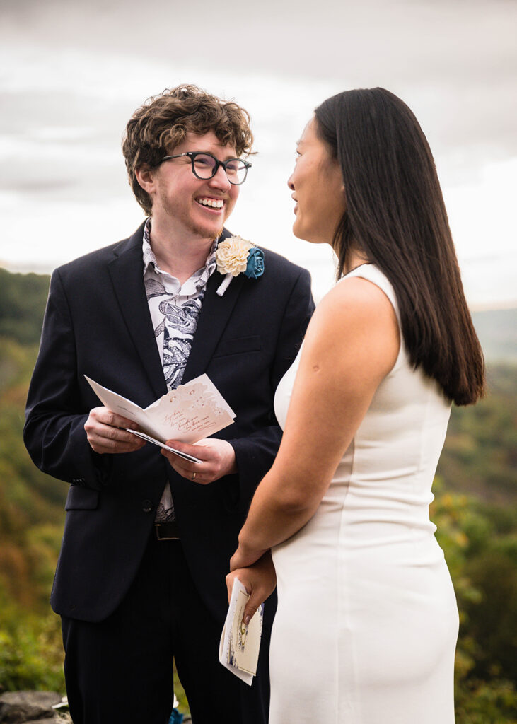 An LGBTQ+ marrier smiles at their partner as they take a moment to react to a card.
