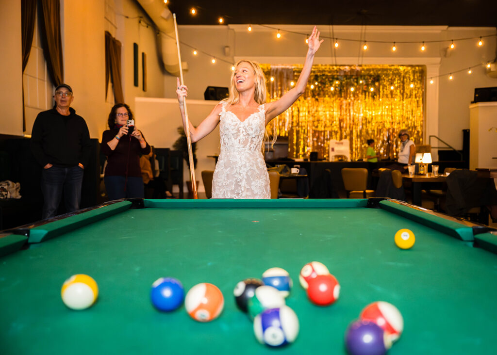 A bride kicks off a round of billiards by "breaking" a set of balls.
