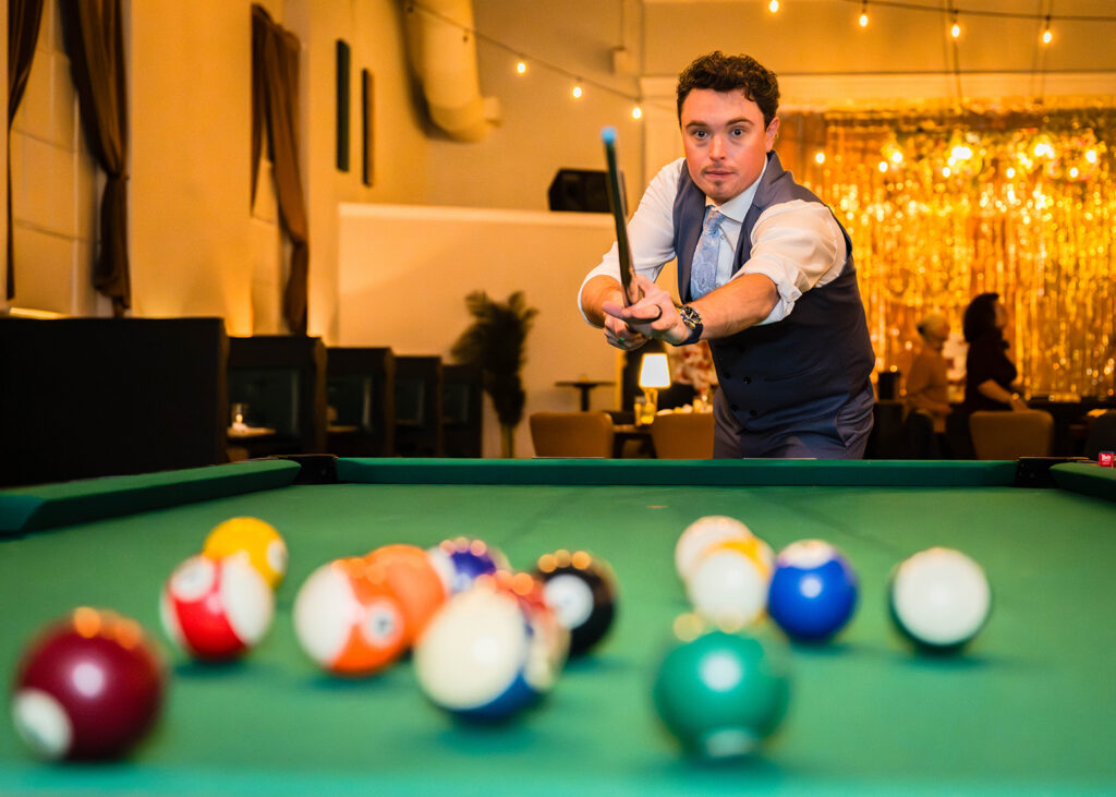 A groom kicks off a game of pool by "breaking" a set of balls.