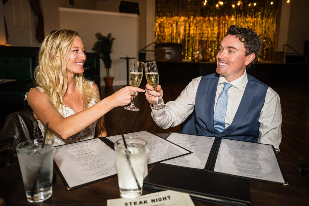 Two marriers sit at a table and clink glasses of champagne at The Black Twig in Sperryville, Virginia.
