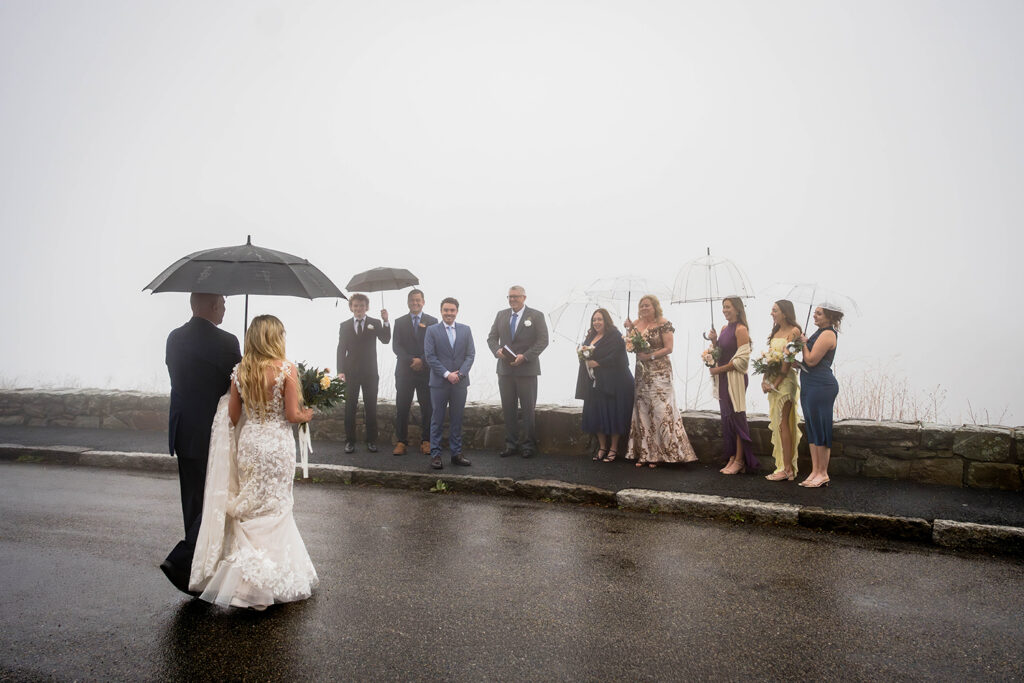 The father of the bride and the bride walk arm-and-arm towards the groom and their families at Thorofare Mountain Overlook.