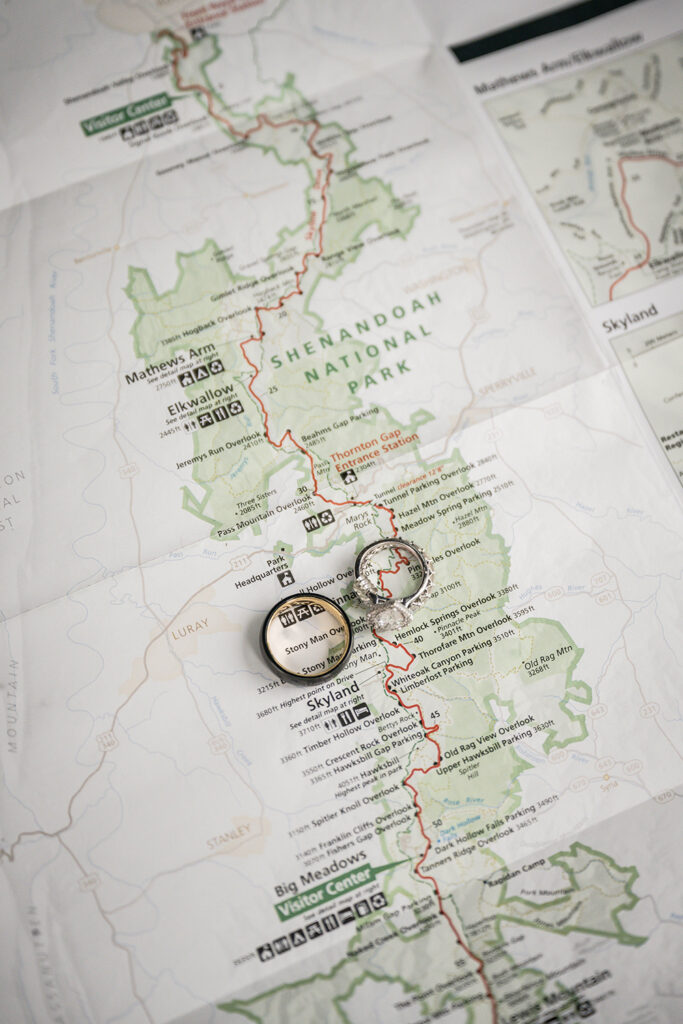A pair of wedding rings are placed on top of a sprawling map of Shenandoah National Park and are purposefully situated near Thorofare Mountain Overlook.