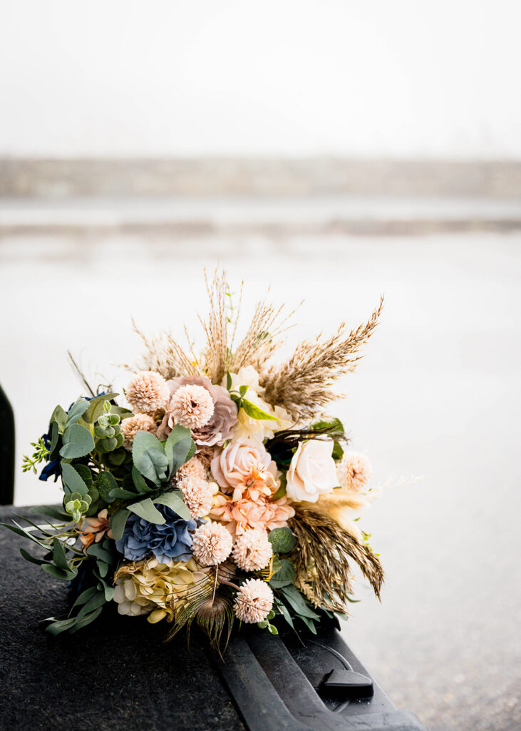 A bouquet of fake flowers on the bed of a truck being photographed against the foggy and rainy Thorofare Mountain Overlook.