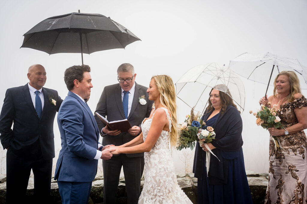 A wedding couple join hands as their parents look towards them during their ceremony at Thorofare Mountain Overlook.